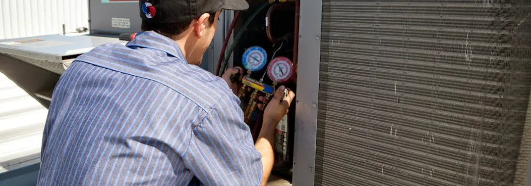 HVAC technician servicing a condenser unit in Fuquay