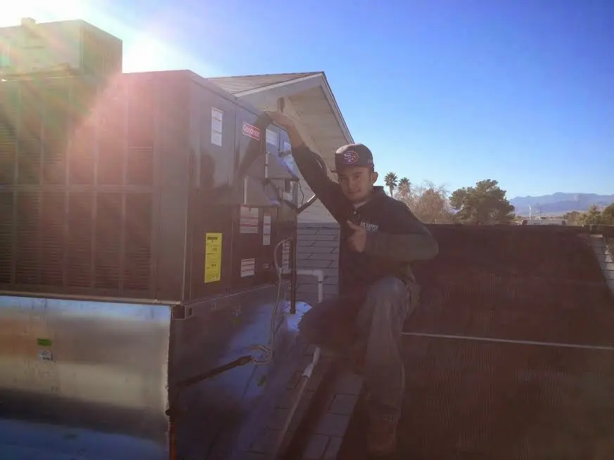 HVAC technician performing Heat Pump Repair on a rooftop unit in Fuquay